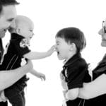 baby squeezing nose of brother with parents taken in manchester studio