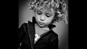 Moody portrait of young boy in black and white vignette