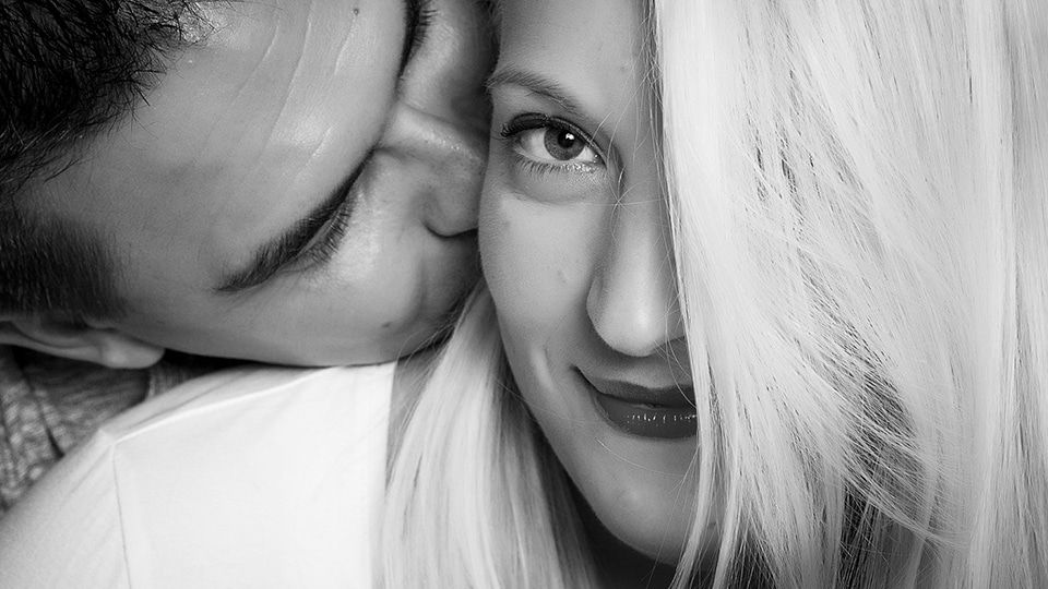 close up portrait of a couple romantic hair covering face in black and white studio