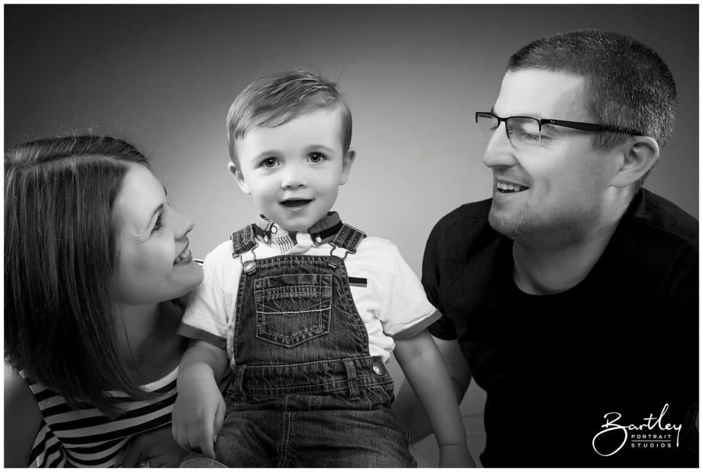 photograph of a family with mum and dad looking at son