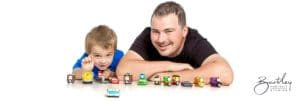 little boy with dad playing with model cars in a photography studio