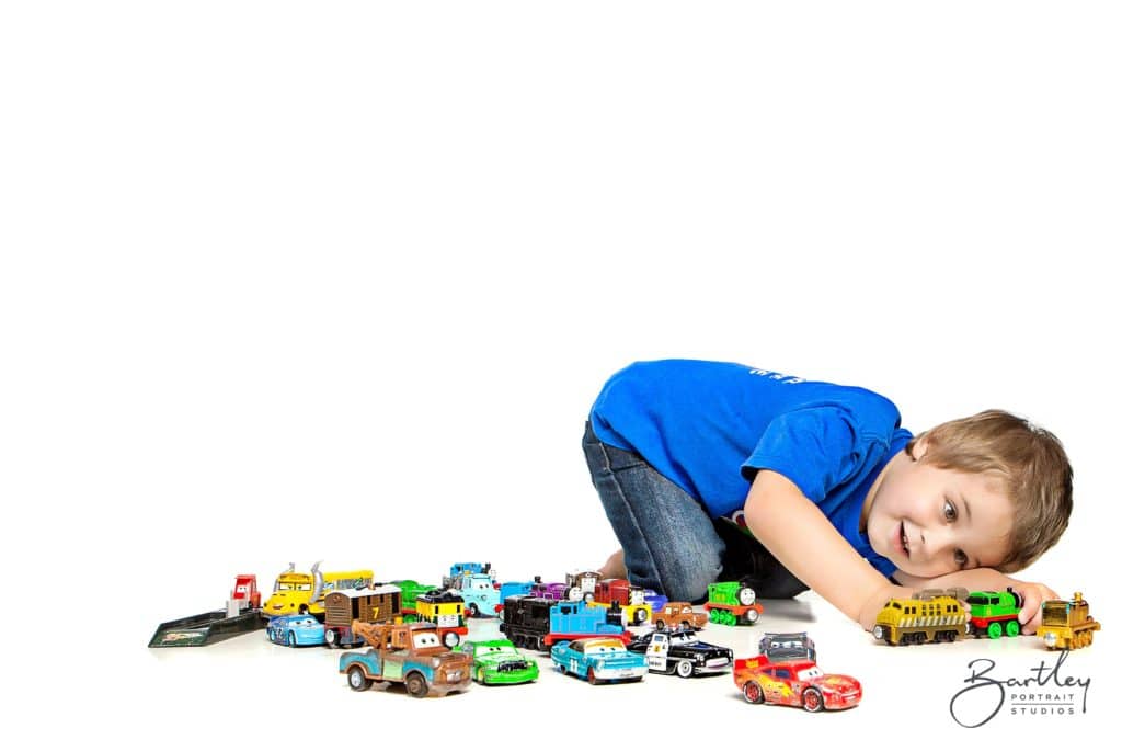 little boy playing with model cars in a photography studio