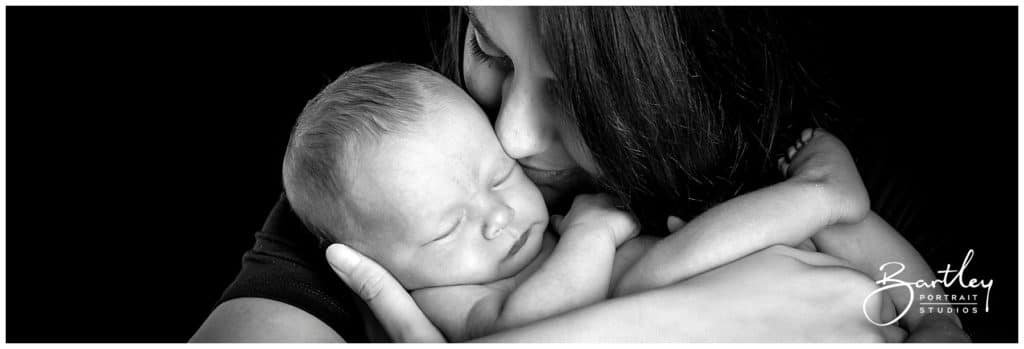 mum kissing newborn baby