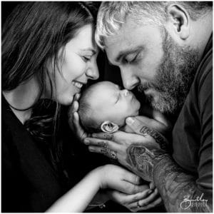 powerful black and white of family holding baby black background