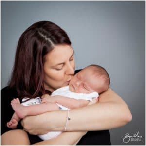 mum holding newborn baby in photography studio