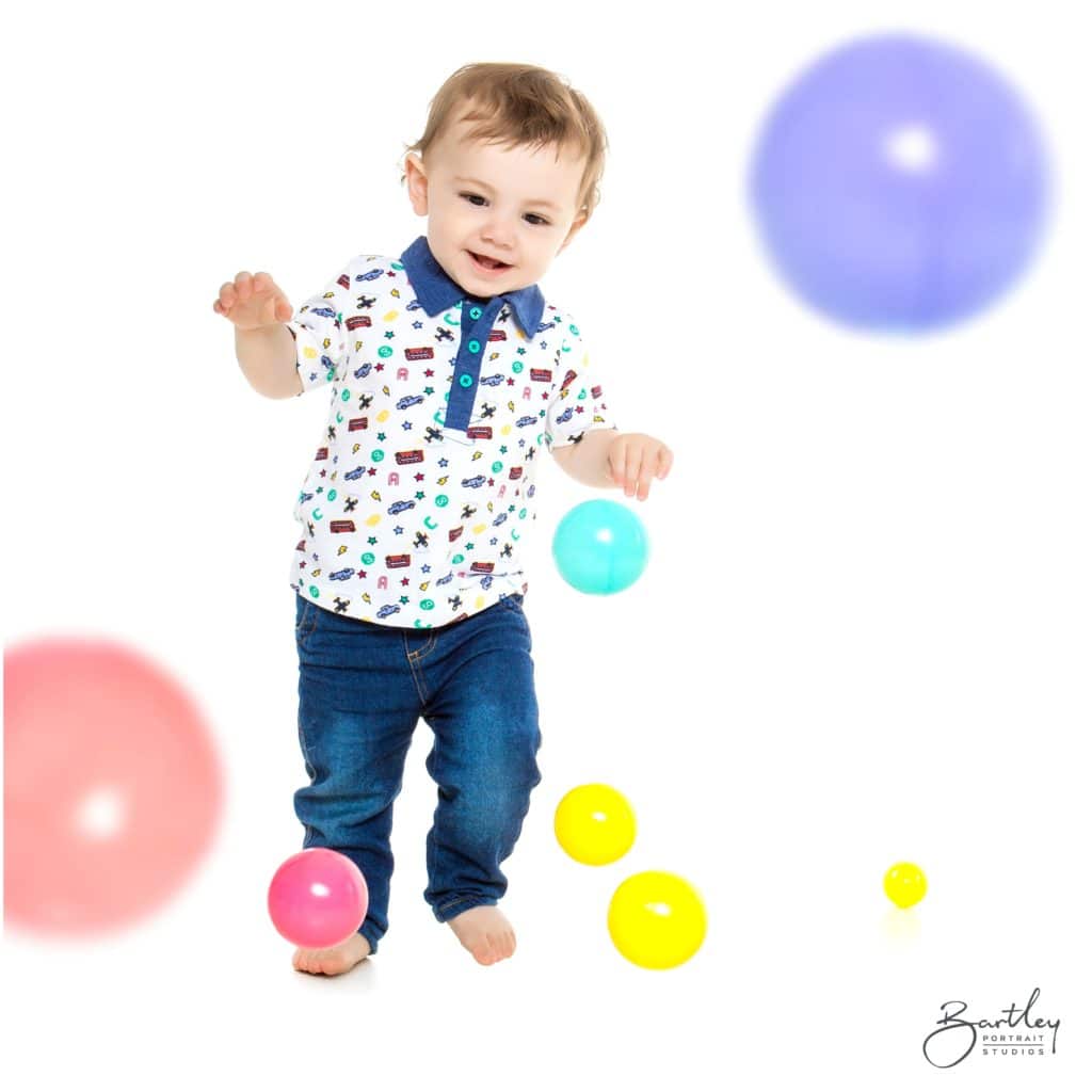 toddler playing in portrait studio with colourful balls