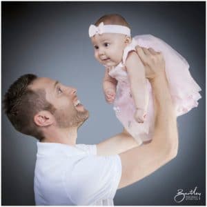 dad holding baby girl in air