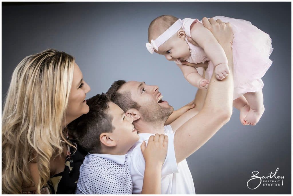 portrait holding baby up in air