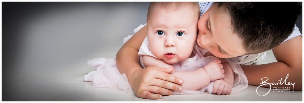 brother kissing baby sister