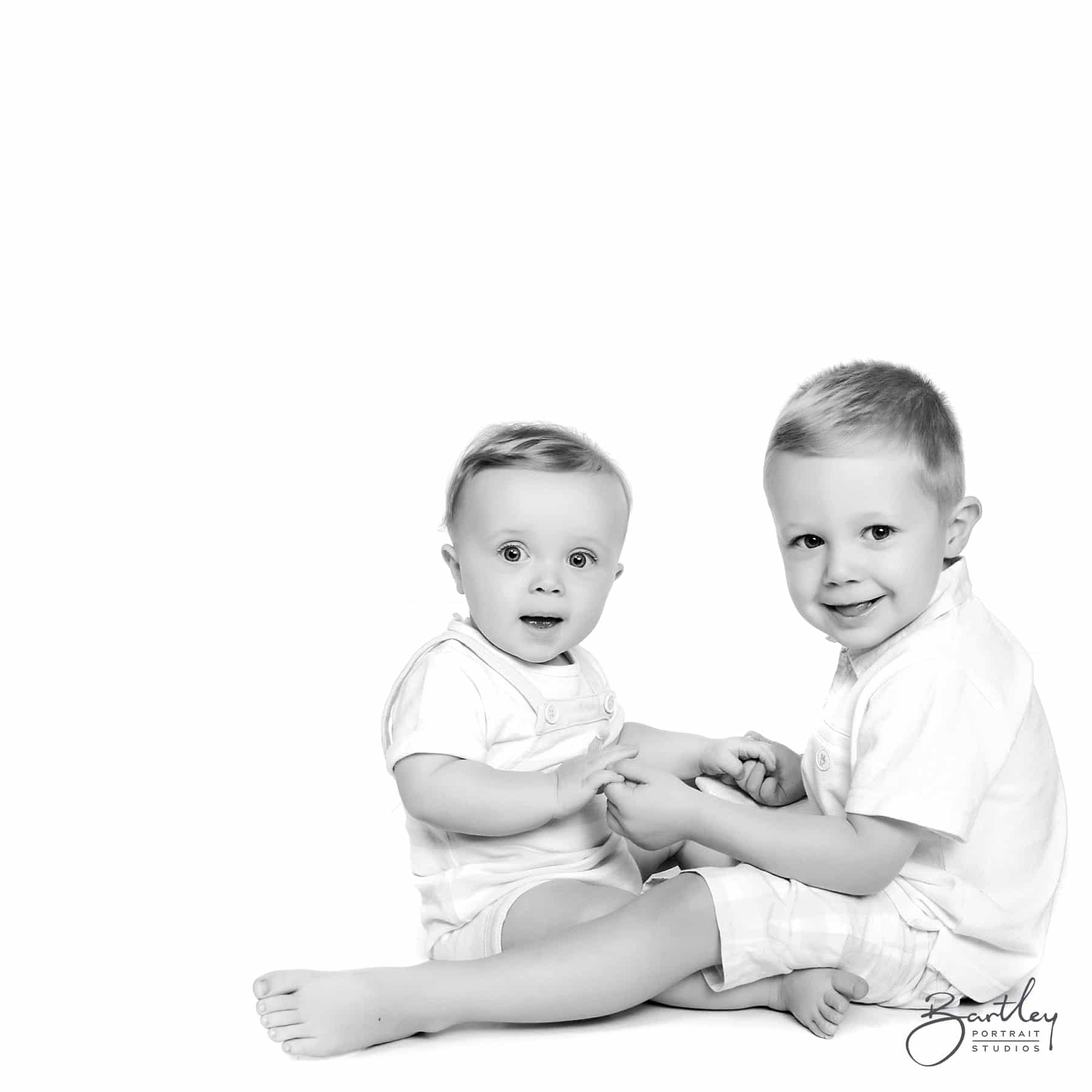 black and white studio shot of brothers holding hands