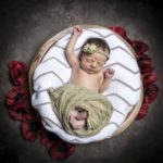 Newborn baby photographed with poppies in a bowl