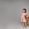 portrait of a little girl in a pink dress with her dog looking into the distance