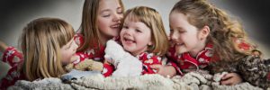 portrait of 3 little sisters laughing and cuddling each other family photoshoot cheshire liverpool manchester warrington